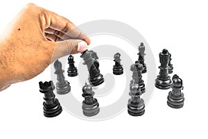 Black colored chess pawns placed over a white background while one person sorting them
