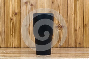 Black colour stainless steel tumbler or cold and hot storage cup on wood
