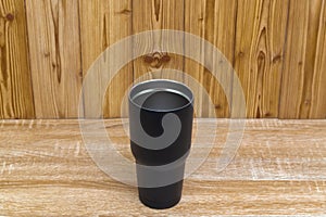 Black colour stainless steel tumbler or cold and hot storage cup on wood