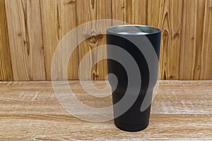 Black colour stainless steel tumbler or cold and hot storage cup on wood