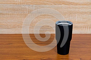 Black colour stainless steel tumbler or cold storage cup on wood