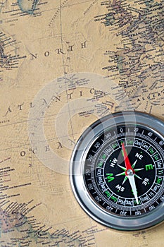 The Black compass on old vintage map, north atlantic ocean, macro background