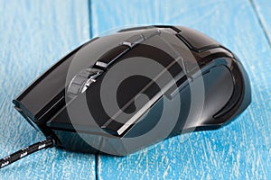 Black computer mouse on a blue wooden background closeup