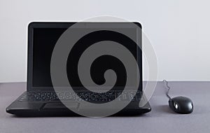 Black computer and mouse on gray table with empty screen