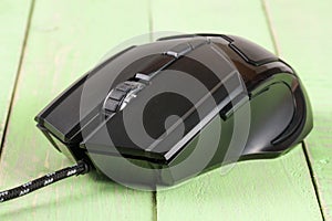 Black computer mouse on a green wooden background closeup