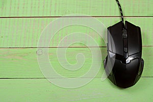 Black computer mouse on a green wooden background with copy space for your text. Top view