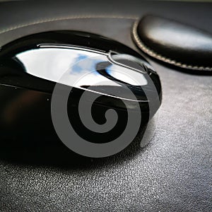 Black computer mouse on a leather pad.