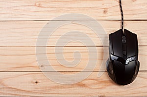 Black computer mouse on a light wooden background with copy space for your text. Top view