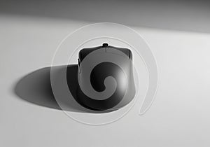 A black computer mouse rests on a smooth, light gray surface. The