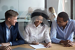 Black confident woman sitting with business partners signing contract