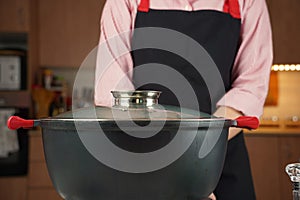 Black cooking pot with a lid on electric hob with boiling water