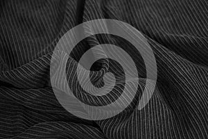 Black corduroy. Soft wavy folds of fabric. Elegant background with copy space