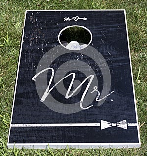 Black cornhole game with Mr written in white text
