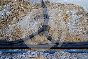 Black corrugated plastic drainage pipes laying in a ditch at a construction site