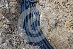 Black corrugated plastic drainage pipes laying in a ditch at a construction site