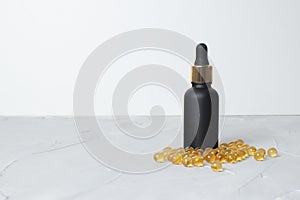 Black Cosmetic bottle with pipette near cod-liver oil on white background