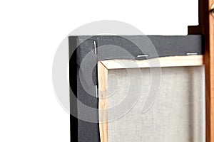 Black cotton canvas stretched on wooden subframe on white background. View from back