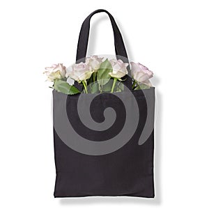 Black cotton tote bag with light violet roses inside. Isolated on white background