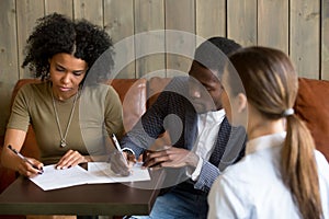 Black couple closing deal by signing contract in cafe