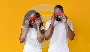 Black couple closing eyes with red valentine cards