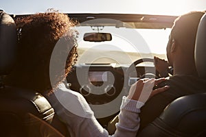 Black couple driving, her hand on his shoulder, back view