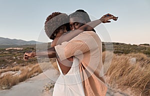 Black couple embracing in nature and looking at camera