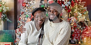 Black couple enjoying Christmas eve, embracing and smiling at camera