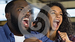 Black couple happy about favorite sports team victory, watching game in pub