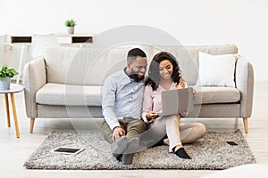 Black couple having video call using laptop waving hands