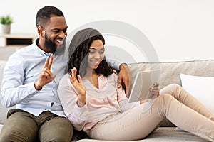Black couple having videocall using digital tablet waving hands