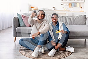 Black couple holding remote controller and debit credit card