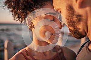 Black couple, hug and touching forehead embracing relationship, compassion or love and care by the beach. Happy man and