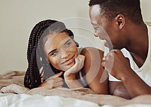 Black couple, love and bedroom conversation while happy together on a bed in a house, apartment or hotel. Face of young