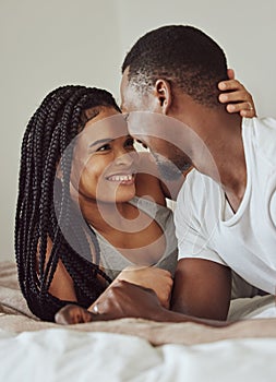 Black couple, love and home bedroom bonding while happy together on a bed in a house, apartment or hotel. Young man and