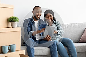 Black Couple Ordering Online With Digital Tablet After Moving To New Apartment