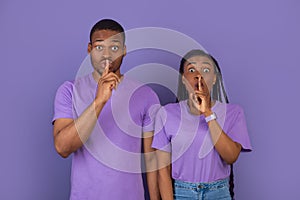 Black couple puting finger on lips, making hush sign
