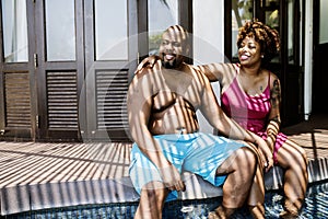 Black couple sitting together at resort poolside