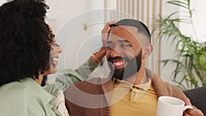 Black couple, smile and relax on sofa together in living room of modern New York apartment while drinking coffee. Happy