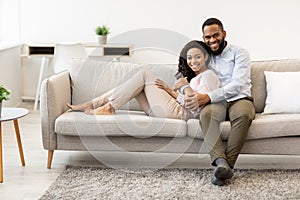 Black couple spending weekend together lying on sofa