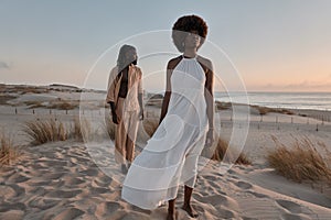 Black couple standing away on sand with dry grass plants in evening light