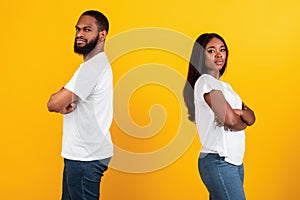 Black couple standing back to back, yellow studio wall