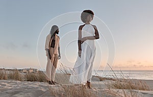 Black couple standing on sandy beach at sunset