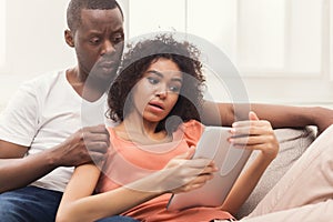 Black couple using digital tablet at home