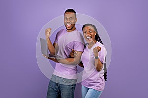 Black couple using laptop celebrating success shaking fists