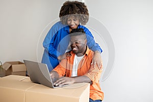 Black Couple Using Laptop After Moving Home, Checking Interior Ideas In Internet