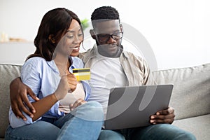 Black couple using pc and credit card at home