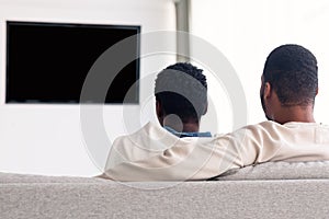 Black couple watching TV with mockup, sitting on the couch