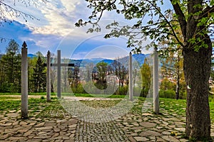 Čierny kríž so stĺpmi obklopený zelenými stromami. Banska Bystrica Calvary, Slovakia.