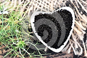 Black cumin nigella sativa or kalonji seeds in heart-shaped bowl