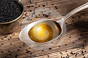 Black cumin seed oil on a spoon with black cumin seeds